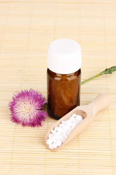 Frasco de medicamento com comprimidos e flor na esteira de bambu — Fotografia de Stock