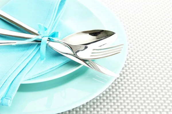 Mavi boş tabak çatal, kaşık ve bıçak üzerinde gri bir masa örtüsü — Stok fotoğraf