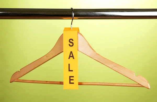 Wooden clothes hanger as sale symbol on green background — Stock Photo, Image