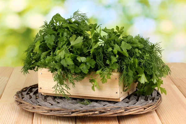 Trälåda med persilja och dill på wicker vagga på träbord på natura — Stockfoto