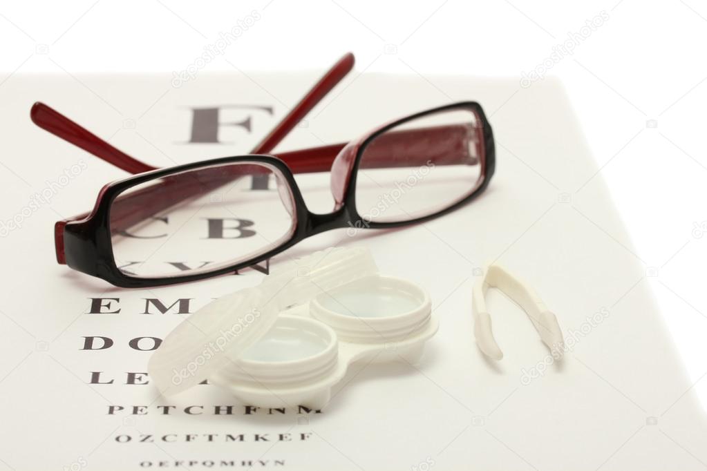 glasses, contact lenses in containers and tweezers, on snellen eye chart ba