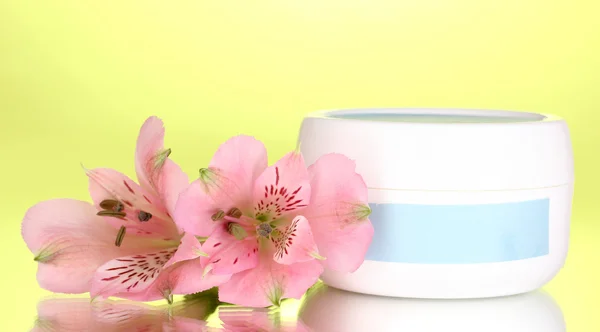 Potje crème met bloem op groene achtergrond — Stockfoto