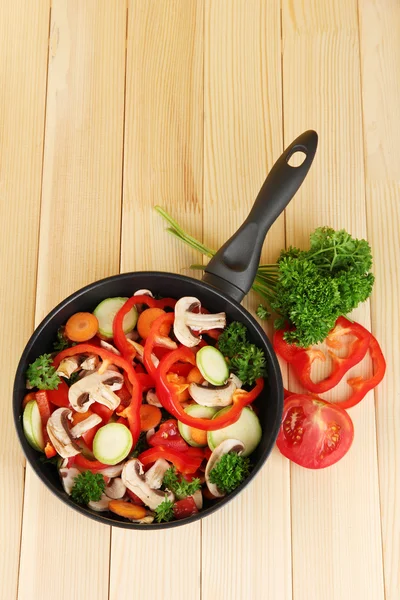 Frying pan with vegetables on wooden background — Stock Photo, Image