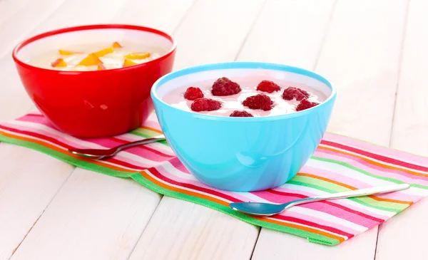 Yogurt with peaches and raspberries in bowls on wooden background — Stock Photo, Image