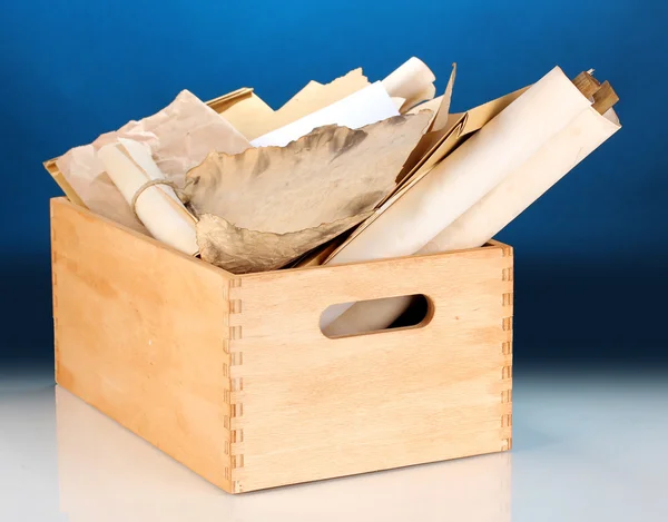 Caisse en bois avec papiers et lettres sur fond bleu — Photo