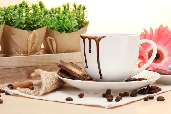 Vuile kopje koffie en gerbera bonen, kaneel stokken op houten tafel — Stockfoto
