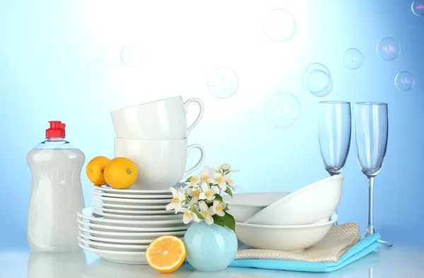 Platos limpios vacíos, vasos y tazas con líquido lavavajillas y limón en b — Foto de Stock