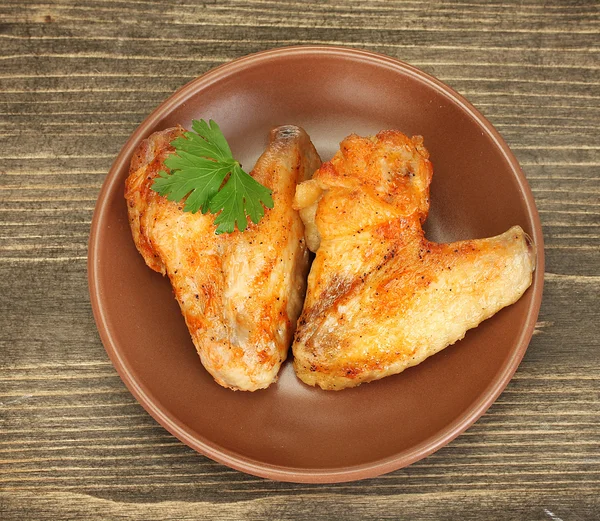 Ailes de poulet rôties avec du persil dans l'assiette sur fond en bois fermer - — Photo