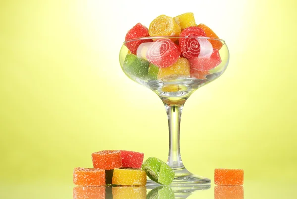 Kleurrijke gelei snoepjes in in cocktailglas op groene achtergrond — Stockfoto