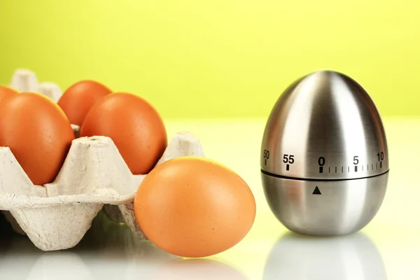 Oeufs dans la boîte et minuterie oeuf sur fond vert — Photo