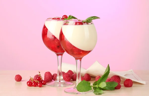 Jelly buah dengan buah dalam gelas di atas meja kayu di latar belakang merah muda — Stok Foto