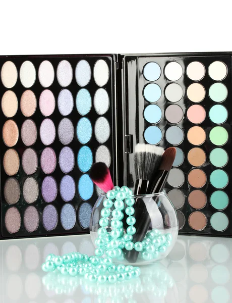 Make-up brushes in a bowl with pearl necklace on palette of shadows backgro — Stock Photo, Image