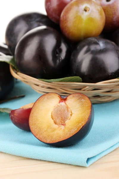 Rip plums on basket close-up on wooden table — Stock Photo, Image