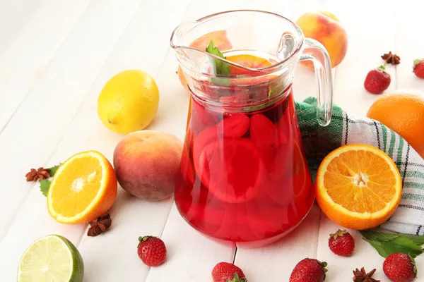 Sangria em jarra com frutos, em mesa de madeira — Fotografia de Stock