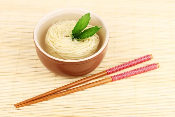 Fideos asiáticos en tazón en estera de bambú — Foto de Stock