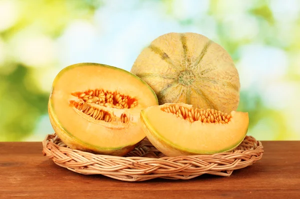 Cut melon on wicker mat on green background close-up — Stock Photo, Image