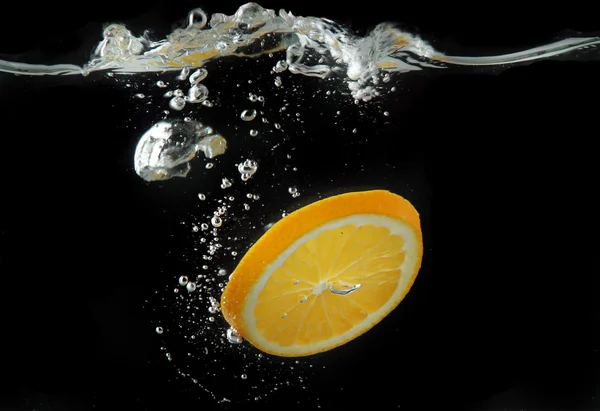 Rebanada de naranja en el agua sobre fondo negro — Foto de Stock