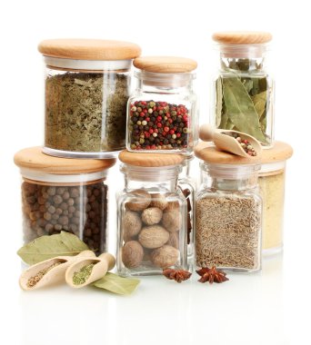 Kavanozlar ve tahta kaşıklar üzerinde beyaz izole baharatlar ile