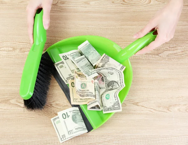 Sweeps money in the shovel on wooden background close-up — Stock Photo, Image