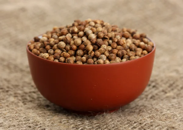 Heap koriander zaden in kom op doek achtergrond close-up — Stockfoto