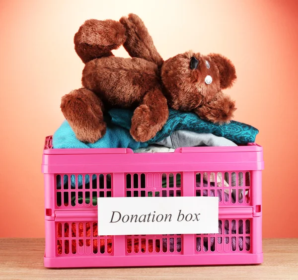 Donation box with clothing on red background close-up — Stock Photo, Image