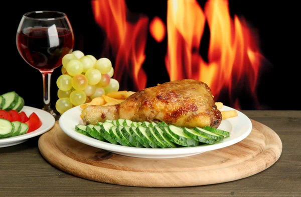Жареная курица с картошкой фри и огурцами, бокал вина на деревянной столешнице — стоковое фото