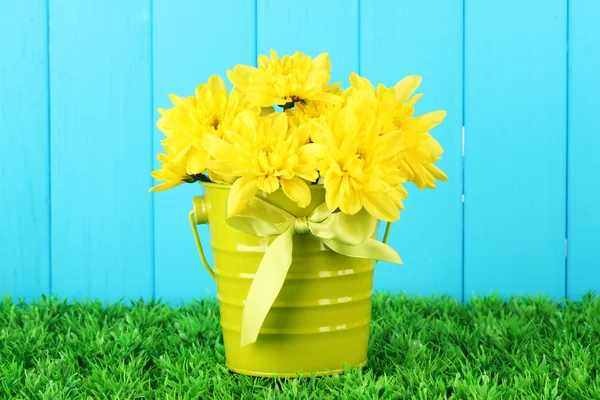 Beautiful bouquet of chrysanthemums in a bright colorful bucket on blue fen — Stock Photo, Image