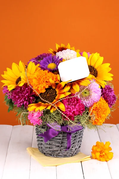 Beautiful bouquet of bright flowers with paper note on wooden table on oran — Stock Photo, Image