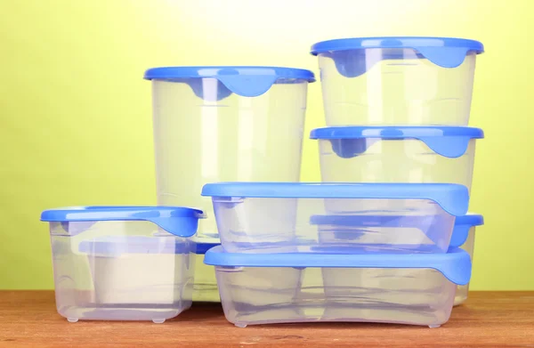 Kunststoffbehälter für Lebensmittel auf Holztisch auf grünem Hintergrund — Stockfoto