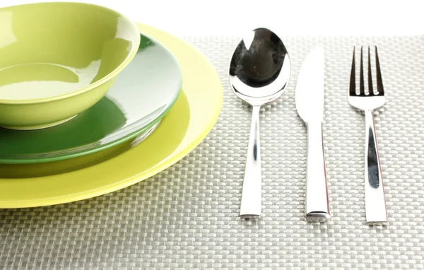 Piatti vuoti verdi con forchetta, cucchiaio e coltello su una tovaglia grigia — Foto Stock