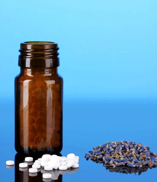 Frasco con pastillas y hierbas sobre fondo azul. concepto de homeopatía — Foto de Stock