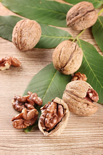 Nueces con hojas verdes, sobre fondo de madera —  Fotos de Stock