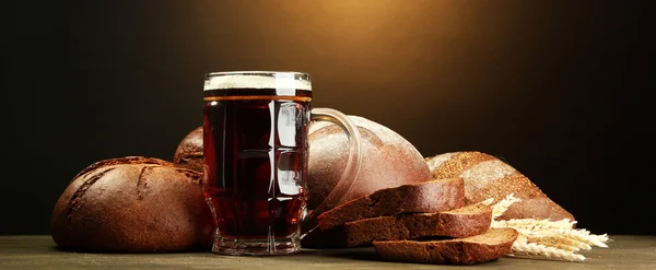Tankard van kvas en rogge brood met oren, op houten tafel op bruine backgro — Stockfoto
