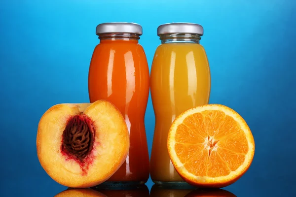 Delicioso suco de laranja e pêssego em garrafa e laranja e pêssego ao lado — Fotografia de Stock