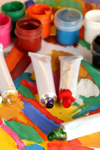 Tubes with colorful watercolor and jars with gouache on colorful picture cl — Stock Photo, Image