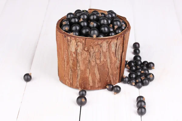 Zwarte bessen in houten cup op houten achtergrond — Stockfoto