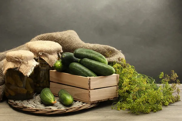 Fresh cucumbers in wooden box, pickles and dill, on grey background — Stock Photo, Image