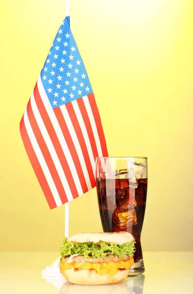 Tasty sandwich and cola with american flag, on yellow background — Stock Photo, Image