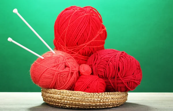 Filati di maglia rossi in cestino su tavolo di legno su sfondo verde — Foto Stock