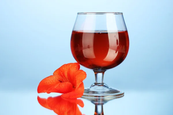 Glas med cocktail och gladiolus bud på blå bakgrund närbild — Stockfoto