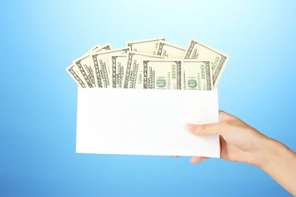 A mão da mulher passa o envelope com o salário no fundo azul — Fotografia de Stock
