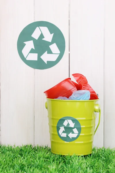 Reciclagem bin na grama verde perto de cerca de madeira — Fotografia de Stock