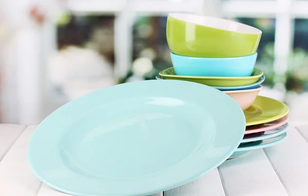 Colorful plates on wooden table on window background — Stock Photo, Image