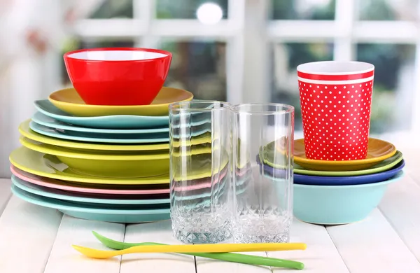 Colorful tableware on wooden table on window background — Stock Photo, Image