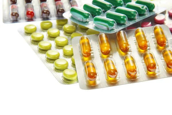 Cápsulas y pastillas envasadas en ampollas, aisladas en blanco — Foto de Stock