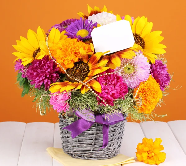 Beautiful bouquet of bright flowers with paper note on wooden table on oran — Stock Photo, Image