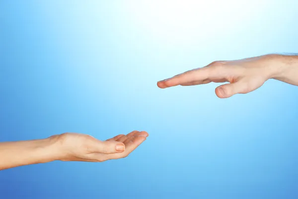 Women's hand goes to the man's hand on blue background Stock Image