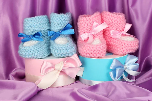 粉色和蓝色婴儿靴子和礼品的丝绸背景 — 图库照片