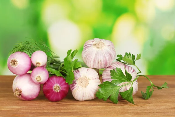 Young garlic and onion on wooden table on bright green background close-up — Stock Photo, Image