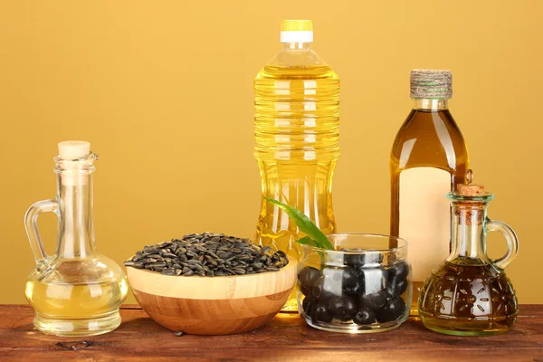 Aceite de oliva y girasol en las botellas y pequeños decantadores sobre fondo amarillo —  Fotos de Stock